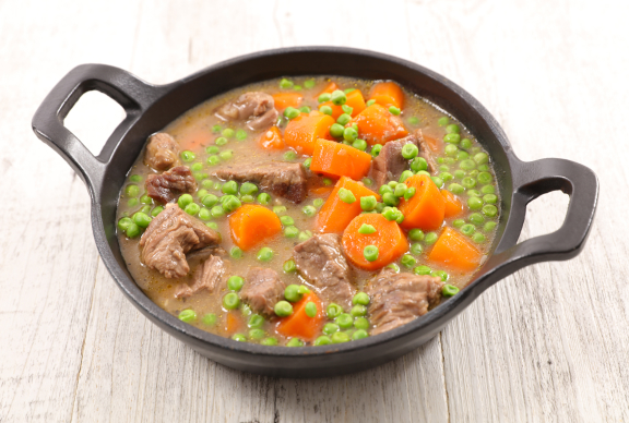 Guiso con zanahoria, carne y guisantes en una cazuela negra