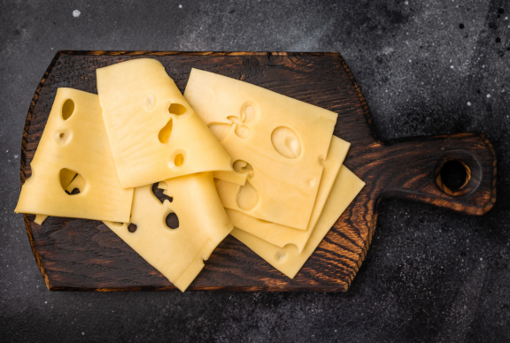 Láminas de queso emmental sobre una tabla de madera