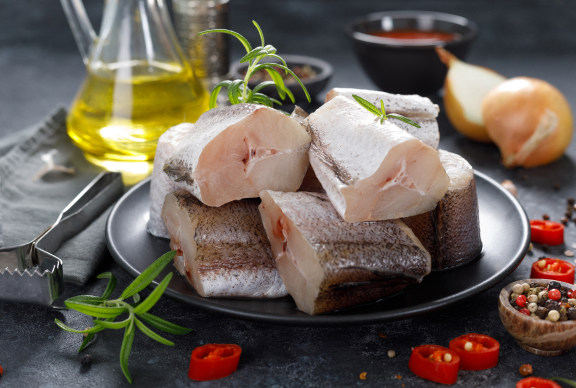 Pedazos de merluza cruda en plato negro