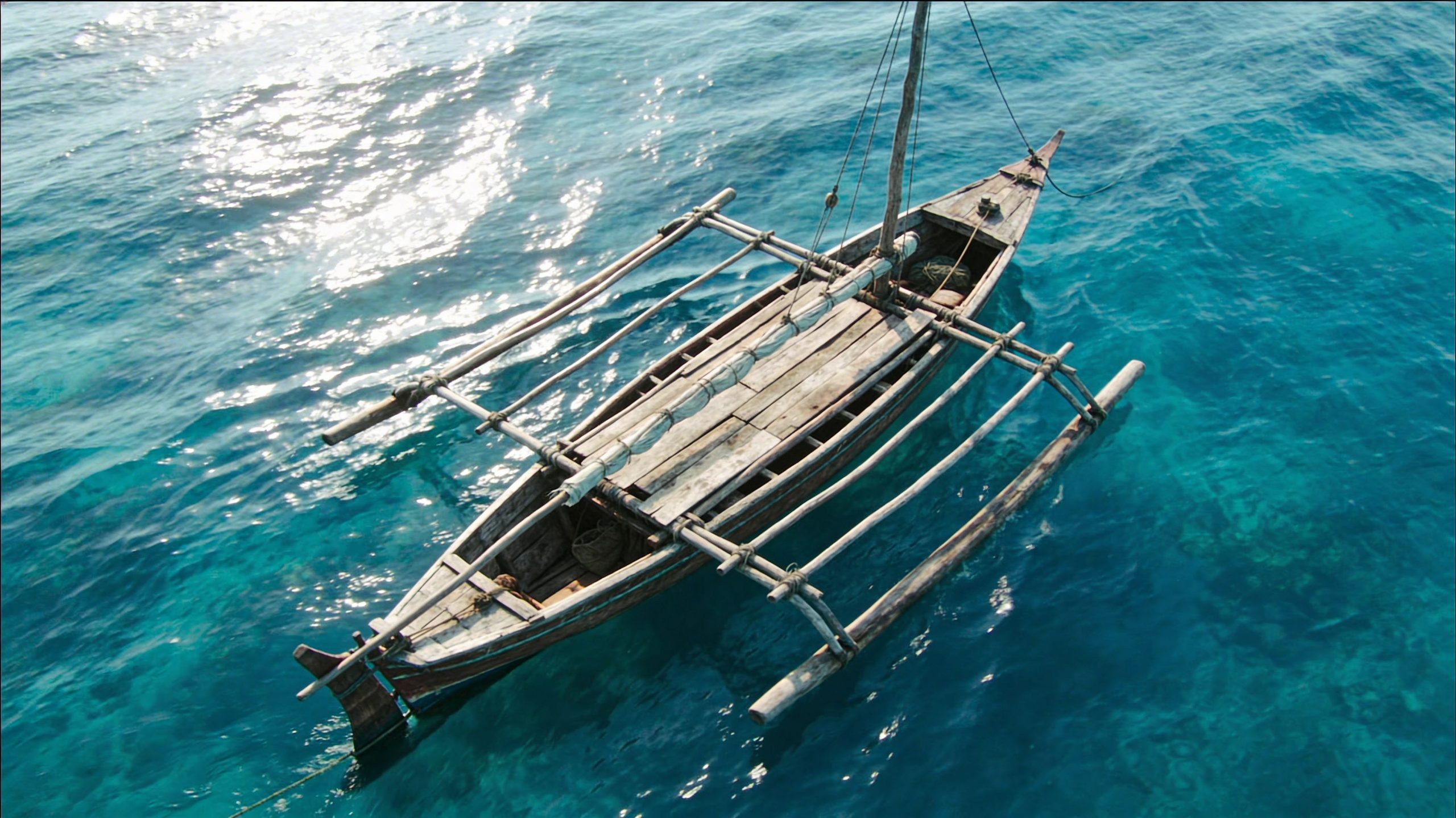 Una embarcación tradicional tipo bangka de madera navegando sobre las aguas cristalinas y brillantes del mar tropical.